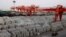 FILE - Workers ride through an aluminum ingots depot in Wuxi, Jiangsu province, China, Sept. 26, 2012. President Donald Trump imposed tariffs on aluminum and steel in March of 2018, with the goal of boosting U.S. production.