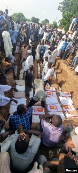 FILE - People place bodies into a mass grave in the aftermath of a strike near a bridge that killed dozens of people in Nyala, Sudan, on Aug. 23, 2023.
