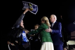 FILE - A protester at left, is held back by Jill Biden, center, and her husband Democratic presidential candidate former Vice President Joe Biden, right, during a primary election night rally in Los Angeles, March 3, 2020.