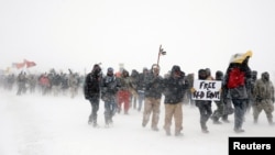 Para aktivis dan veteran yang berdemonstrasi di luar kamp Oceti Sakowin menentang pembangunan jalur pipa minyak di Reservasi suku asli Standing Rock, dekat Cannon Ball, North Carolina, Desember 2016.