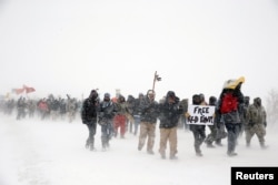 FILE - Veterans join activists in a march just outside the Oceti Sakowin camp during a snow fall as "water protectors" continue to demonstrate against plans to pass the Dakota Access pipeline adjacent to the Standing Rock Indian Reservation, Dec. 5, 2016.