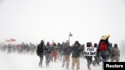 Veterans join activists in a march just outside the Oceti Sakowin camp during a snow fall as "water protectors" continue to demonstrate against plans to pass the Dakota Access pipeline adjacent to the Standing Rock Indian Reservation, near Cannon Ball, North Dakota.