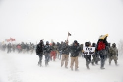 Veterans join activists in a march just outside the Oceti Sakowin camp during a snow fall as "water protectors" continue to demonstrate against plans to pass the Dakota Access pipeline adjacent to the Standing Rock Indian Reservation.