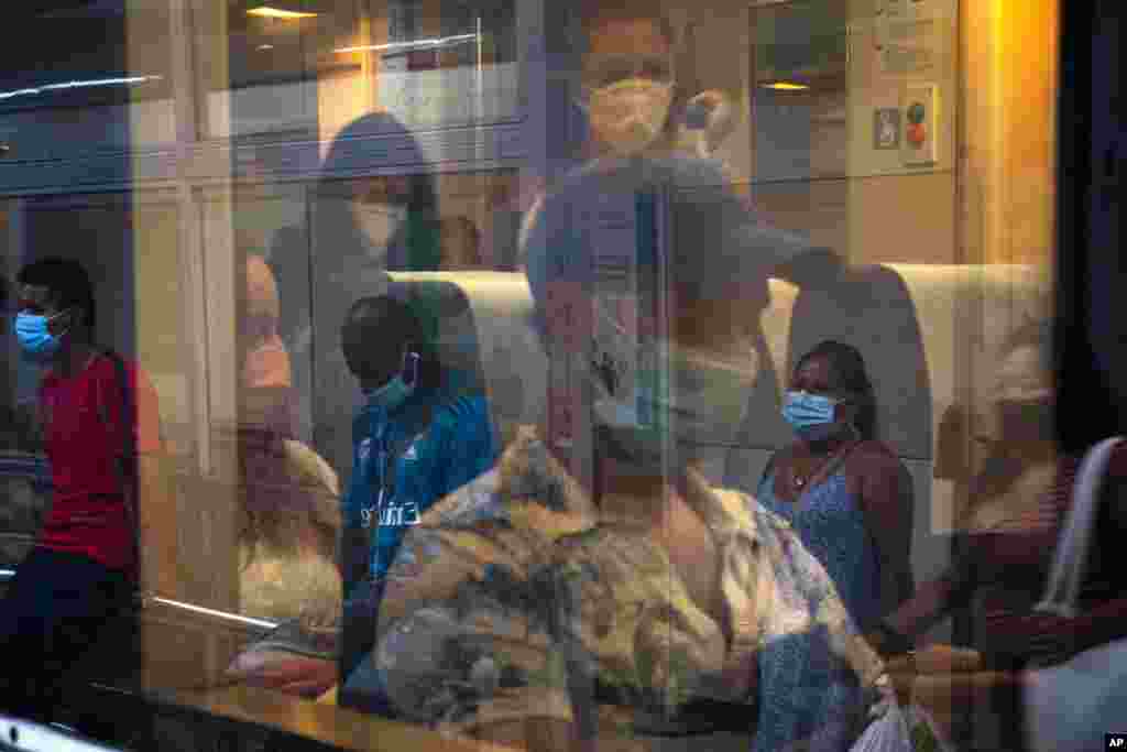 Passengers wearing face masks travel on a train at the main train station in Barcelona, Spain.