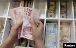 FILE - A money changer counts Turkish lira bills at an currency exchange office in central Istanbul, Turkey, Aug. 21, 2015.