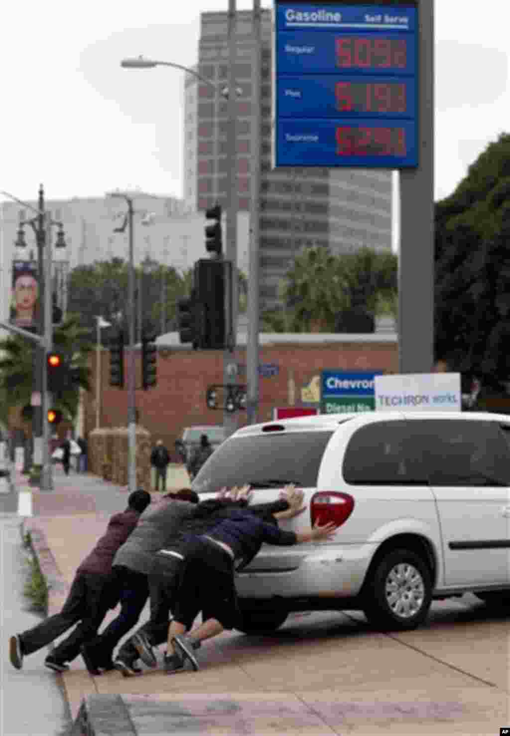 Pedrestrians help push a motorist who ran of gas into a station downtown Los Angeles on Friday, March 16, 2012. Higher gas prices could force consumers to cut back on discretionary spending and could weigh on growth and slow hiring in the nation.(AP Photo