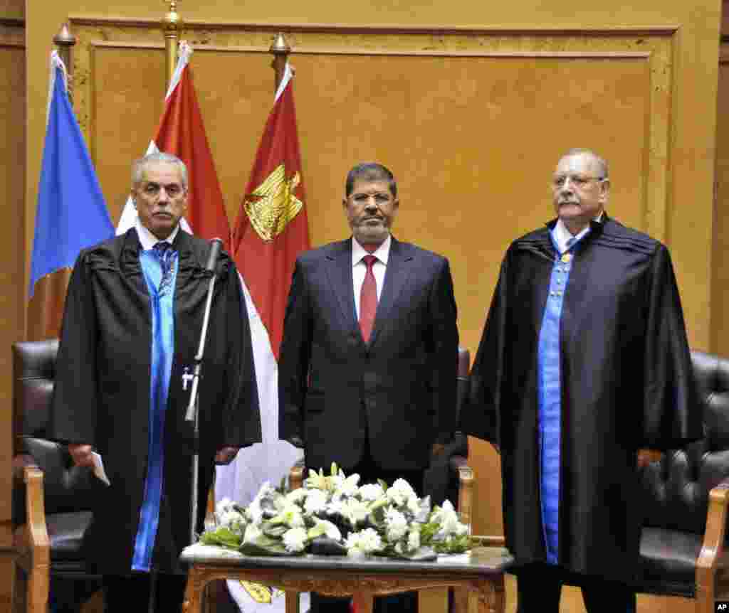Egyptian President Mohammed Morsi, center, stands as he is sworn in at the Supreme Constitutional Court in Cairo, Egypt, June 30, 2012.