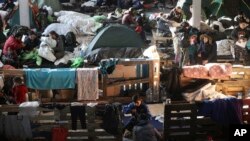 Migrants settle in the logistics center of the checkpoint "Bruzgi" at the Belarus-Poland border near Grodno, Belarus, Wednesday, Dec. 1, 2021.