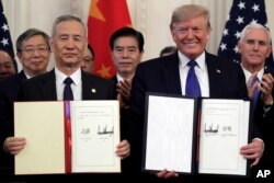 President Donald Trump signs a trade agreement with Chinese Vice Premier Liu He, in the East Room of the White House, Jan. 15, 2020, in Washington.