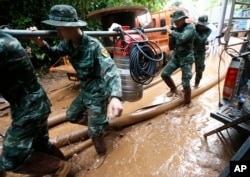 Soldiers carry a pump to help drain the rising floodwater in a cave where 12 boys and their soccer coach have been missing in Mae Sai, Chiang Rai province, northern Thailand, June 29, 2018.
