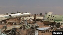 Un combattant des Forces démocratiques syriennes (FDS) marche au milieu des carcasses d’avions détruits à l’aéroport militaire de Tabqa repris des mains du groupe Etat islamique, à l’ouest de Raqa, Syrie, 9 avril 2017.