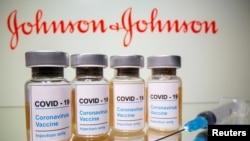 FILE - Vials with a sticker reading, "COVID-19 / Coronavirus vaccine / Injection only" and a medical syringe are seen in front of a displayed Johnson & Johnson logo in this illustration, Oct. 31, 2020. 