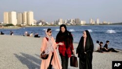 Women walk on the shore of the Persian Gulf Martyrs' Lake in Tehran, Iran, July 6, 2019. A few daring women in Iran's capital have been taking off their mandatory headscarves, or hijabs, in public, risking arrest.