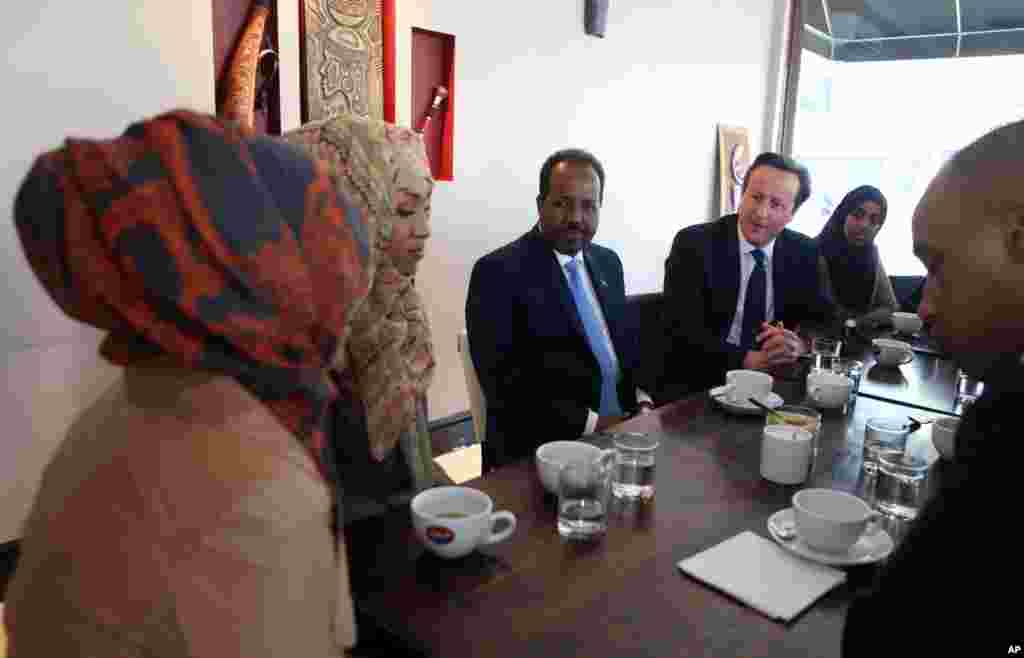 Somali President Hassan Sheikh Mohamud listens as Britain's Prime Minister David Cameron speaks with members of the Somali diaspora living in Britain in London, May 7, 2013.