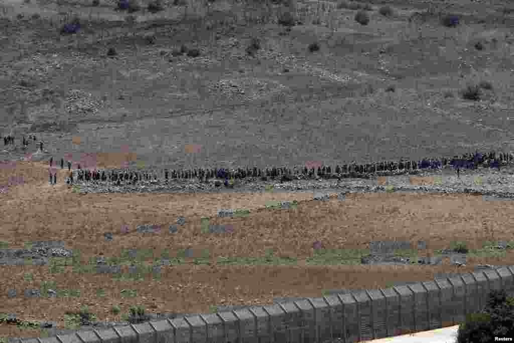 People start to walk away from the border fence between Israel and Syria at its Syrian side as it is seen from the Israeli-occupied Golan Heights near the Israeli Syrian border.