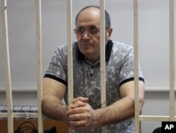FILE - Oyub Titiev, the head of a Chechnya branch of the respected human rights group Memorial, stands behind bars in court before a hearing in Grozny, Russia, Sept. 28, 2018.