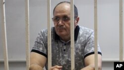 Oyub Titiev, the head of a Chechnya branch of the respected human rights group Memorial, stands behind the bars in court before a hearing in Grozny, Russia, Sept. 28, 2018.
