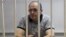 Oyub Titiev, the head of a Chechnya branch of the respected human rights group Memorial, stands behind the bars in court before a hearing in Grozny, Russia, Sept. 28, 2018.