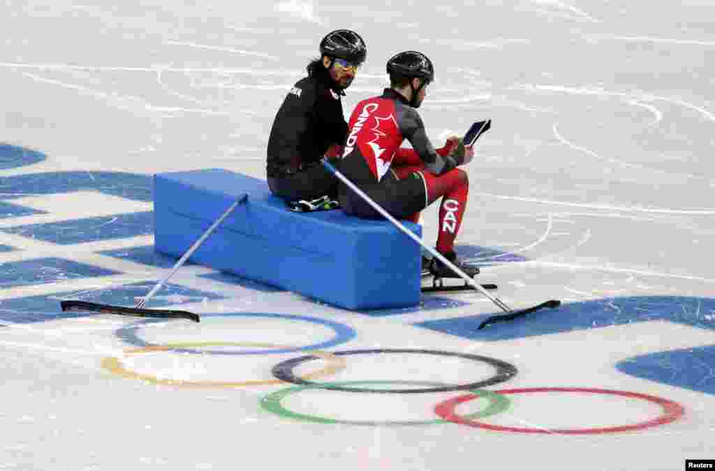 Canadian short track speed skaters and brothers Charles and Francois Hamelin watch a replay of their training on an iPad at the Iceberg Skating Palace, Feb. 4, 2014. 
