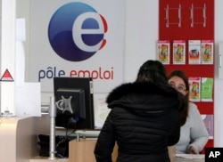 FILE - A job seeker speaks to a clerk at an Employment Center in Marseille, southern France, Feb. 24, 2015. Record-high unemployment started dragging French President Francois Hollande's popularity down just a few months after his election in 2012.