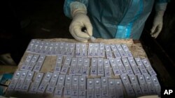 A health worker performs tests after taking nasal swab samples to test for COVID-19 in Gauhati, India, Aug. 7, 2020.