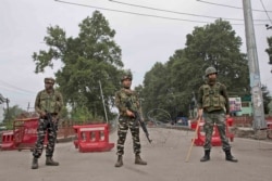Indian paramilitary soldiers stand guard near a temporary check post on the road leading towards Independence Day parade venue during lockdown in Srinagar, Indian-controlled Kashmir, Aug. 15, 2019.