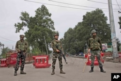 Indian paramilitary soldiers stand guard near a temporary check post on the road leading towards Independence Day parade venue during lockdown in Srinagar, Indian-controlled Kashmir, Aug. 15, 2019.