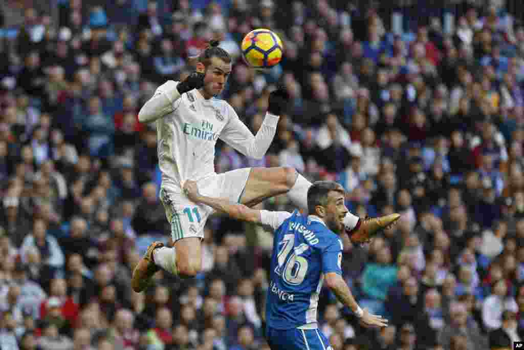 Real Madrid&#39;s Gareth Bale, top, outjumps Deportivo Coruna&#39;s Luisinho during a Spanish La Liga soccer match between Real Madrid and Deportivo Coruna at the Santiago Bernabeu stadium in Madrid, Spain.