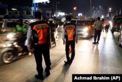 Para petugas Dishub dan polisi menjaga pos pemeriksaan di Cibitung, Bekasi, Jawa Barat, saat penerapan larangan mudik nasional untuk mencegah penyebaran pandemi COVID-19, Minggu, 9 Mei 2021. (Foto: Achmad Ibrahim/AP)