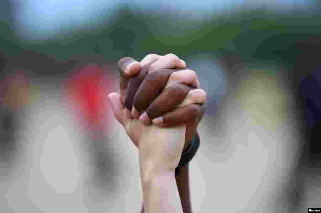 A man and a woman hold hands aloft in Hyde Park during a &quot;Black Lives Matter&quot; protest in London, following the death of George Floyd who died in police custody in Minneapolis, USA.