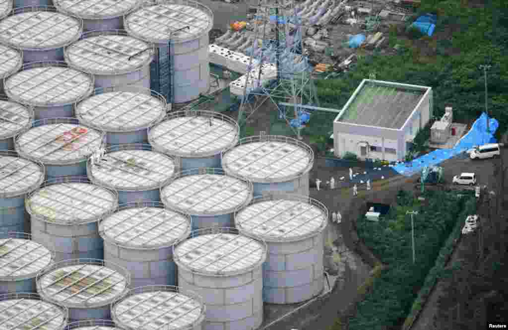 An aerial view shows workers wearing protective suits and masks working atop contaminated water storage tanks at the Fukushima Daiichi nuclear power plant in this photo taken by Kyodo, August 20, 2013.