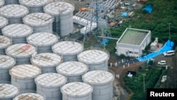 FILE - An aerial view shows workers wearing protective suits and masks working atop contaminated water storage tanks at the Fukushima Daiichi nuclear power plant, Aug. 20, 2013.