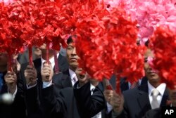 North Koreans wave plastic flowers during a military parade in Pyongyang to celebrate the 105th birth anniversary of Kim Il Sung, the country's late founder and grandfather of current ruler, Kim Jong Un, April 15, 2017.