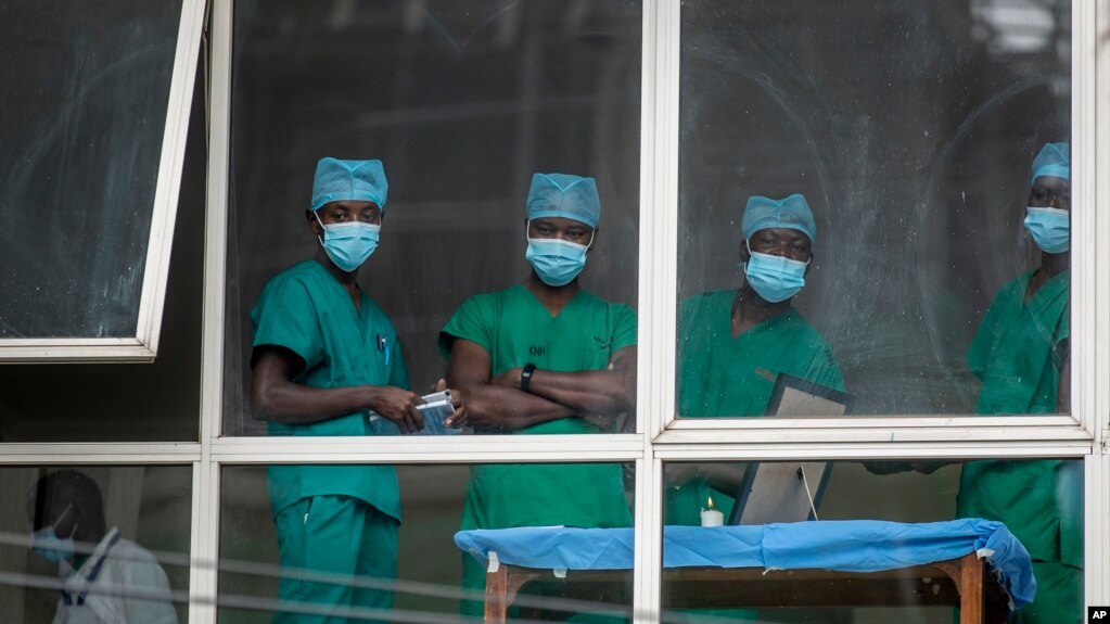 In this March 5, 2021, file photo, medical staff look out from a window as officials prepare for a ceremony to commence the country's first coronavirus vaccinations using AstraZeneca provided through the global COVAX initiative, at Kenyatta National Hospi