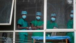 In this March 5, 2021, file photo, medical staff look out from a window as officials prepare for a ceremony to commence the country's first coronavirus vaccinations using AstraZeneca provided through the global COVAX initiative, at Kenyatta National Hospi