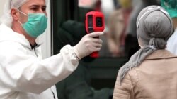 A health worker measures the temperature of a woman outside a hospital in Sarajevo, May 26, 2020