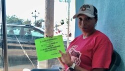 Felicia Rangel, 45, points to a sign she printed out to head off frequent questions in the camp. It says, “the bridge remains closed… asylum cases are not being processed.” (Dylan Baddour/VOA)