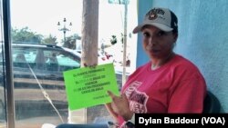 Felicia Rangel, 45, points to a sign she printed out to head off frequent questions in the camp. It says, “the bridge remains closed… asylum cases are not being processed.” (Dylan Baddour/VOA)