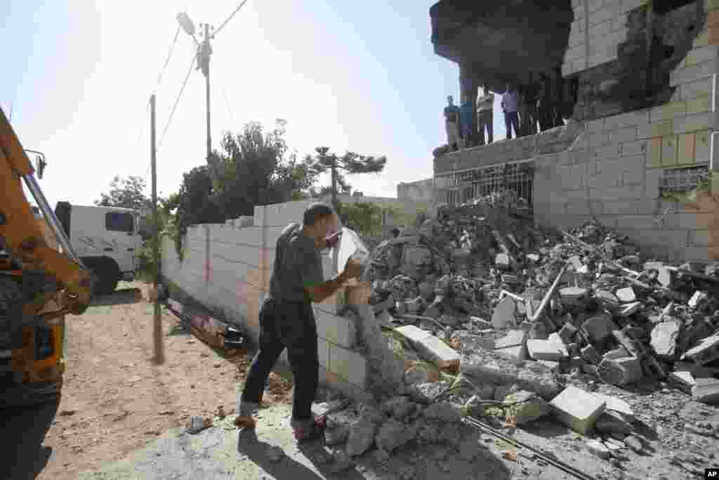 A Palestinian man inspects the damaged house of Amer Abu Aisheh, one of the three Palestinians identified by Israel as suspects in the killing of three Israeli teenagers. The home was demolished by the Israeli army, in the West Bank city of Hebron, Aug. 18, 2014.