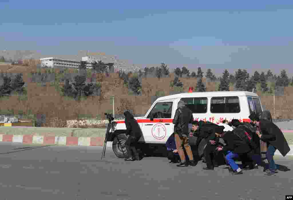 Para jurnalis Afghanistan&nbsp; bersembunyi di balik mobil ambulans di dekat Hotel Intercontinental saat terjadi bentrokan antara kawanan bersenjata dan pasukan keamanan Afghanistan di Kabul.