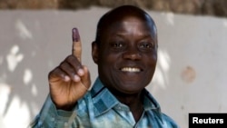 FILE - PAIGC party's candidate Jose Mario Vaz shows his inked finger after voting in Bissau, Guinea-Bissau, April 13, 2014.