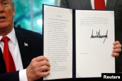U.S. President Donald Trump displays an executive order on immigration policy after signing it in the Oval Office at the White House in Washington, June 20, 2018.