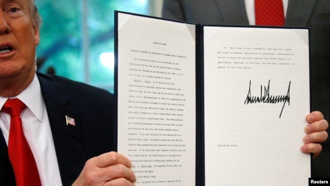 El presidente Donald Trump muestra una orden ejecutiva sobre la política de inmigración después de firmarla en la Oficina Oval en la Casa Blanca en Washington, junio 20, 2018.