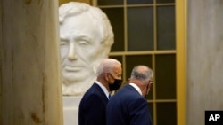 President Joe Biden walks past a statue of former President Abraham Lincoln with Senate Majority Leader Chuck Schumer of N.Y., after arriving on Capitol Hill, Jan. 6, 2022, to speak at a ceremony marking the one year anniversary of the Jan. 6 attack on the U.S. Capitol.