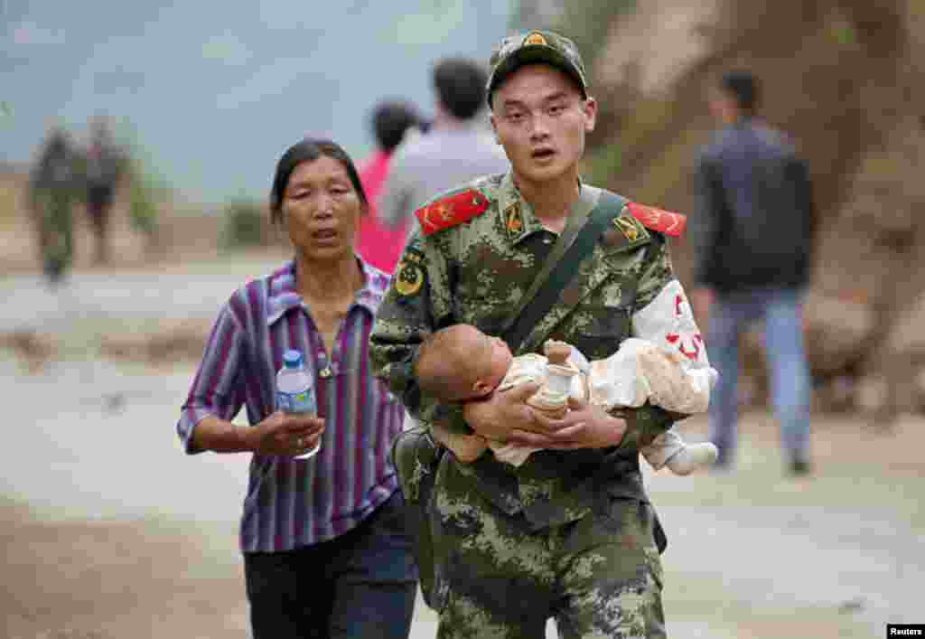 Cảnh sát bán quân sự bế một em bé trên tay sau một trận động đất tại thị trấn Long Đầu Sơn của huyện Lư Điền, tỉnh Vân Nam, Trung Quốc, ngày 3/8/2014. &nbsp;