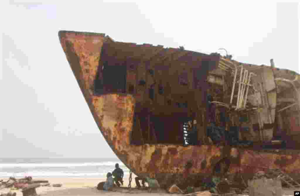Workers gather in the shade of a derelict ship beached against the coastline of Nigeria.