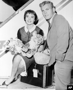 Actress Natalie Wood, left, and actor Tab Hunter pose at the TWA baggage claim at Idlewild Airport in New York City, after arriving from Los Angeles, Aug. 21, 1956.