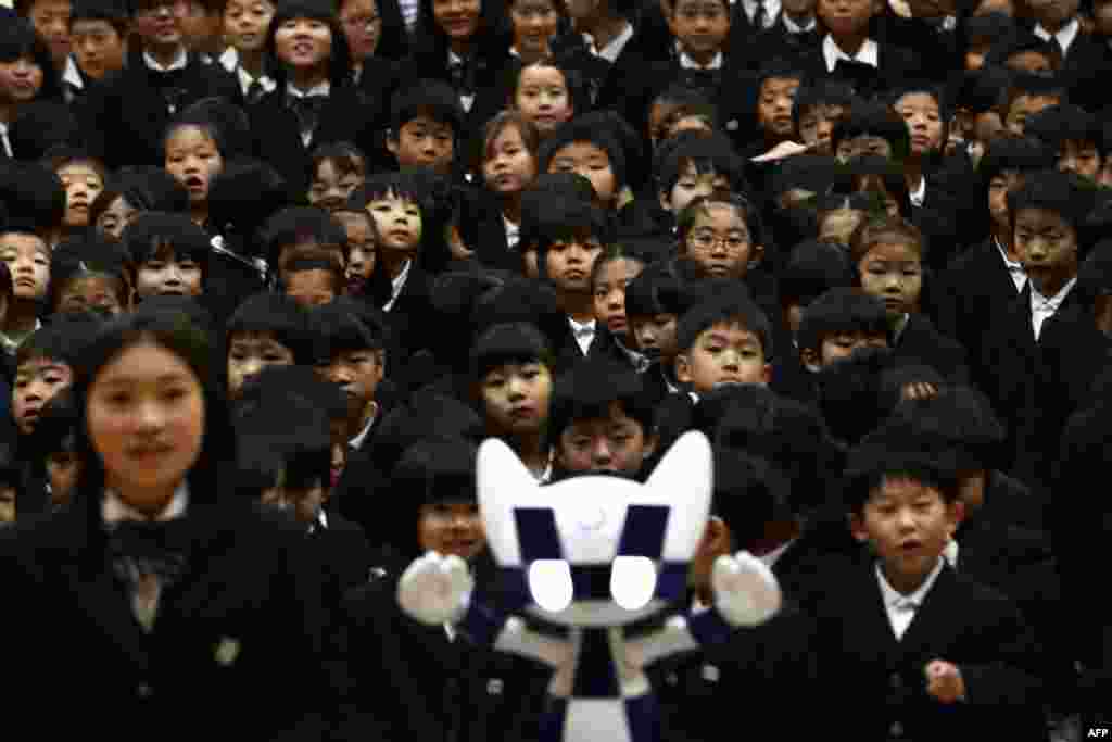 Schoolchildren pose for a picture with Tokyo 2020 Olympic Games' robot-type mascot Miraitowa during a ceremony at Hoyonomori elementary school in Tokyo, Japan.