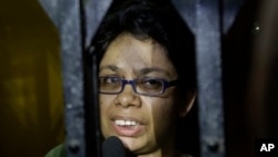 Agnes D'Souza, sister of Judith D'Souza who was kidnapped in Afghanistan, talks to journalists from behind the front gate of their apartment in Kolkata, India, Friday, June 10, 2016. The 40-year-old worker was hired by the Aga Khan Foundation