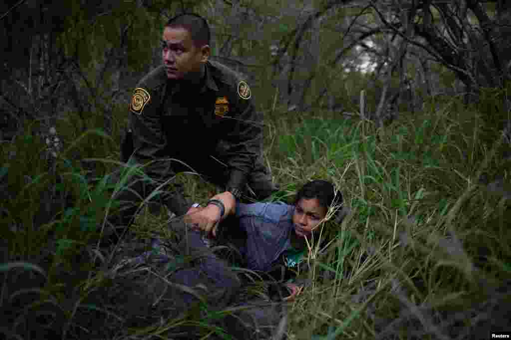 A border patrol agent apprehends a woman and a man after they were caught illegally crossing into the U.S. border from Mexico near McAllen, Texas,, May 2, 2018.